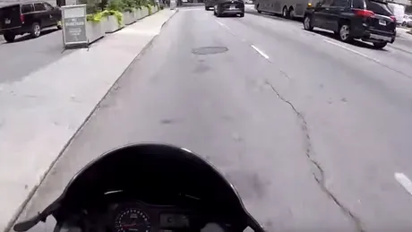 Un şofer îi taie calea unui motociclist care îi aterizează pe capotă şi apoi îi sparge parbrizul - VIDEO