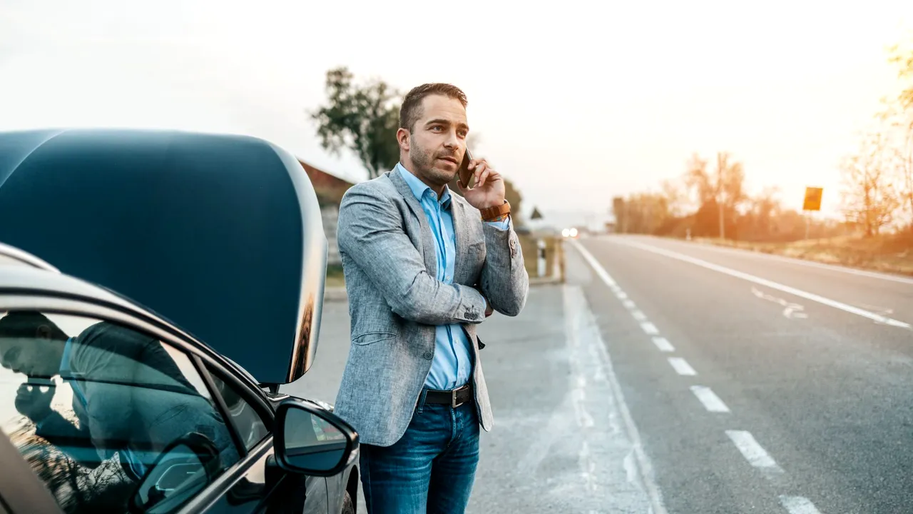 ElegantMiddleAgeBusinessManCallingTowingServiceForHelp 