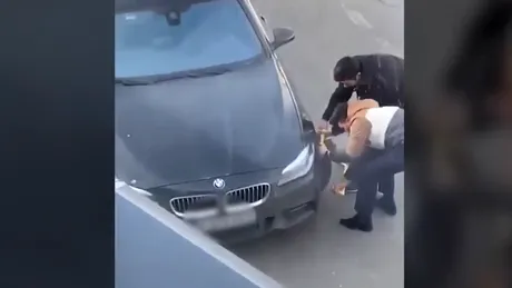 Un șofer de BMW este filmat în timp ce încearcă să dea jos dispozitivul de blocare a roții. În spatele lui apare un polițist - VIDEO