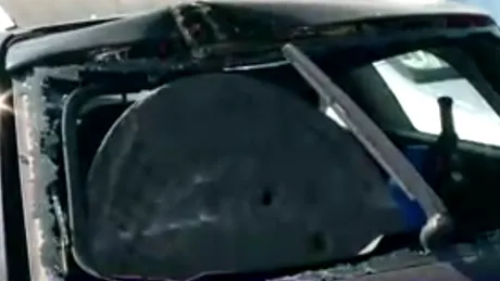 Un capac de canal a spart luneta unei maşini parcate pe marginea drumului -  FOTO