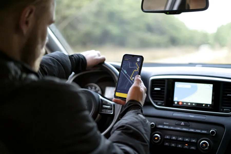 barbat conduce cu telefonul in mana