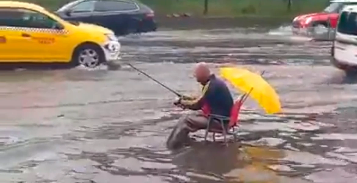 Bucureştean filmat vineri în timp ce ”pescuia” în mijlocul unei străzi inundate. Ce i-au urat şoferii – VIDEO