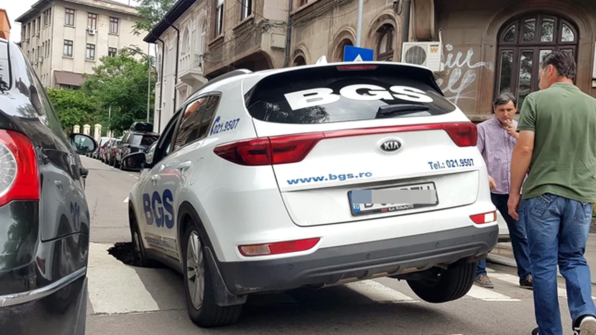 Asfaltul s-a surpat şi o maşină a căzut cu roata într-o groapă în centrul Bucureştiului - VIDEO