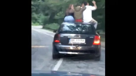 Patru tineri filmaţi pe capota unei maşini aflate în mers - VIDEO