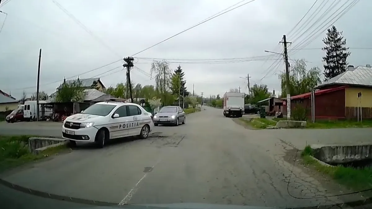 Momentul în care un polițist vrea să vireze la stânga cu autospeciala Dacia Logan, dar lovește un cap de pod
