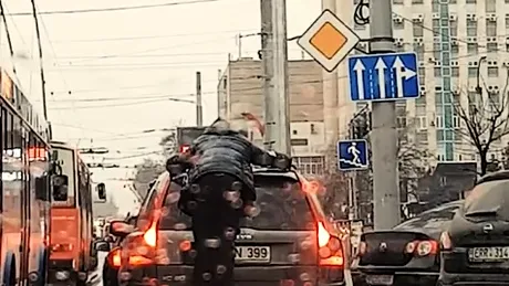 Imagini incredibile: O șoferiță conduce în timp ce un bărbat se află pe mașina sa