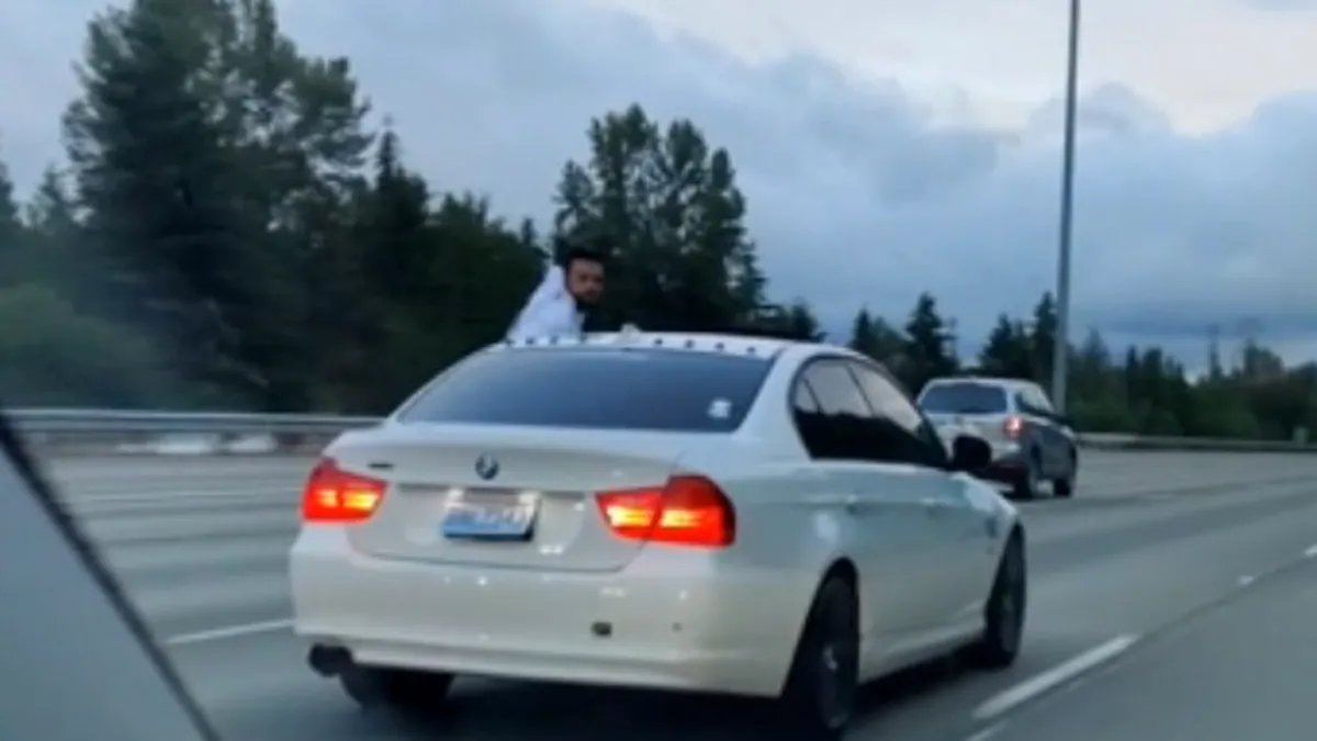 Șofer de BMW filmat pe autostradă, ieșit jumătate pe geam