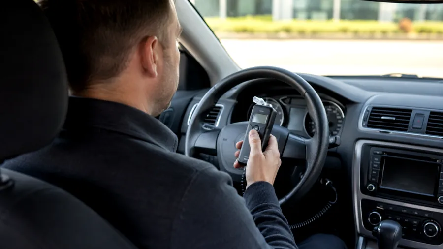 Un sofer care are masina cu sistem „Alcolock” este obligat sa sufle in etilotest pentru a putea porni vehiculul (Imagine generata de inteligenta artificiala: ChatGPT)